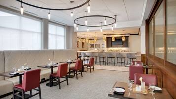 A modern restaurant with booths, high tables, and bar seating.
