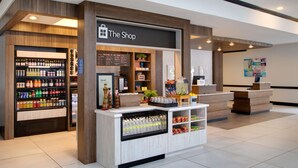 A hotel lobby with a reception desk, a refreshment kiosk, and a display of local delicacies.