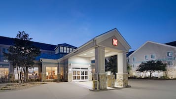 A hotel entrance with a covered walkway, stone pillars, and a clear sky.