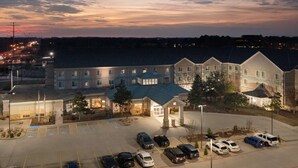 A hotel with a parking lot, multiple vehicles, and a sunset sky.