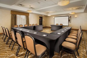 A conference room with a long table, chairs, a projector screen, and a carpeted floor. - Holiday Inn Express Hotel & Suites Columbia East - Elkridge by IHG (Elkridge)