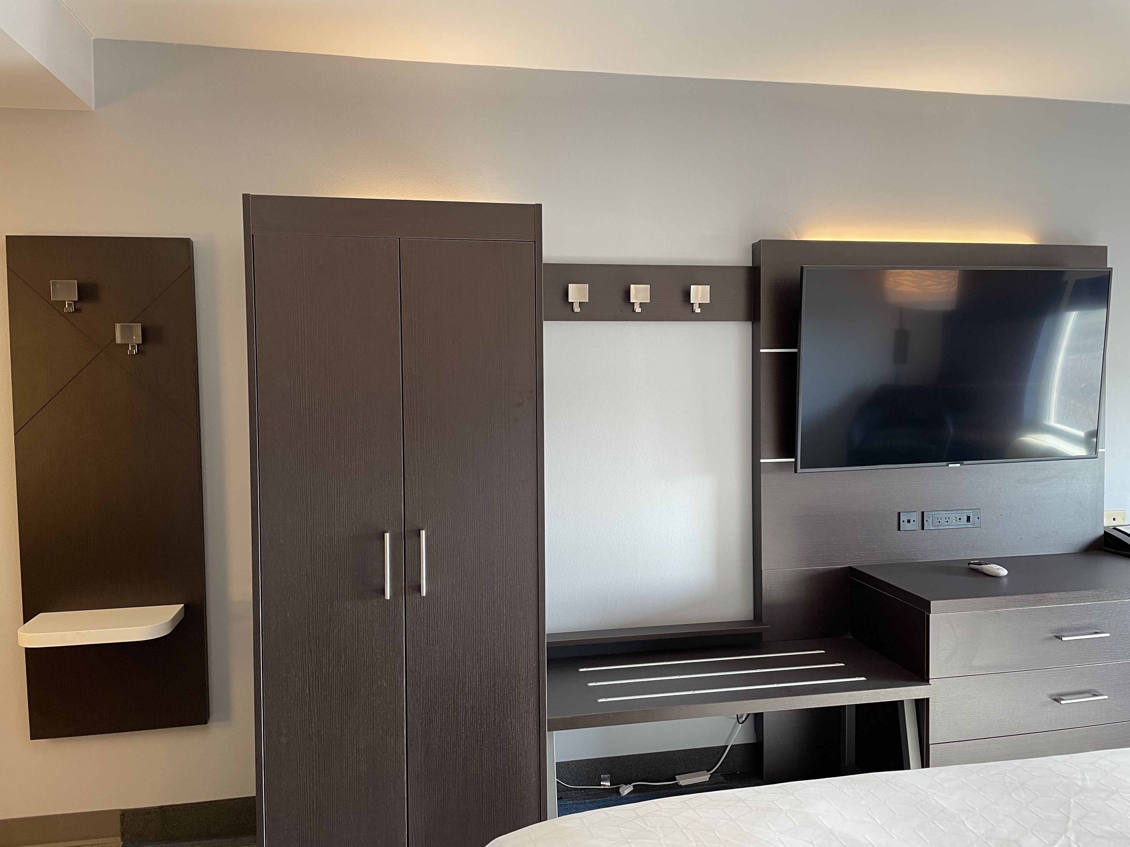 Un dormitorio moderno con un armario grande, un televisor de pantalla plana y una mesita de noche.
