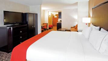 A hotel room with a large bed, a TV, a desk, and a chair.