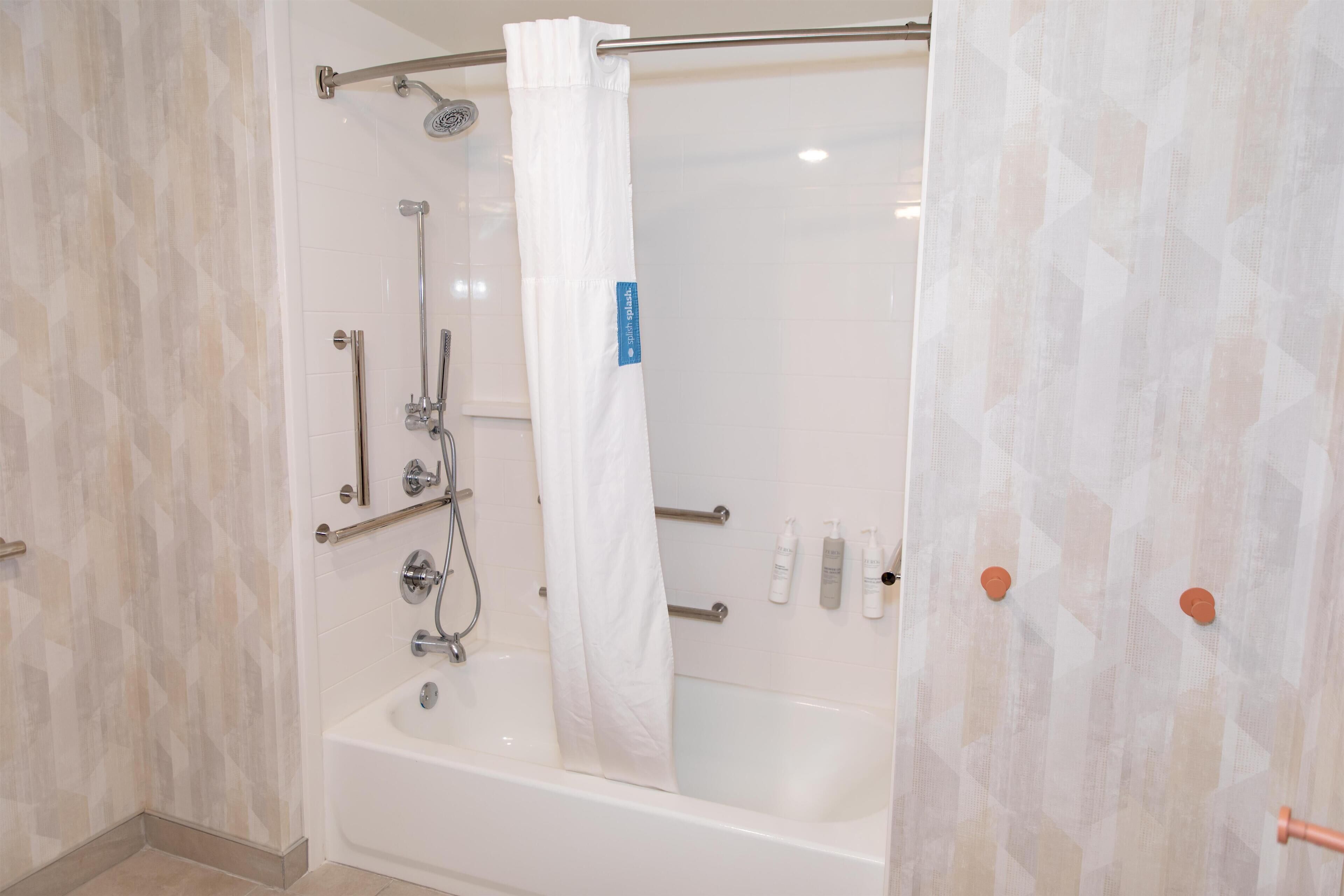 Un baño moderno con bañera, ducha y barras de apoyo.