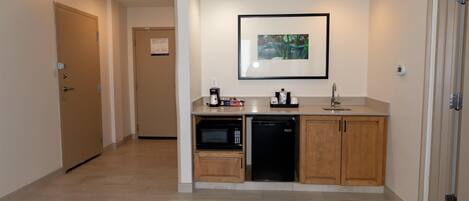 A compact kitchen with a microwave, dishwasher, and a framed picture on the wall.