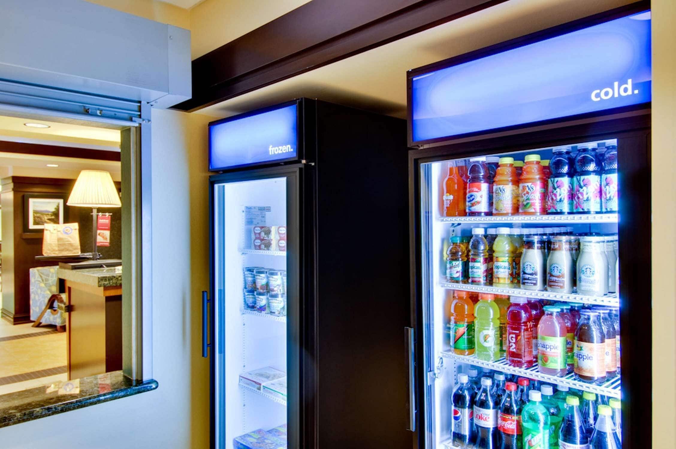 Una habitación de hotel con minibar, refrigerador y dispensador de bebidas.
