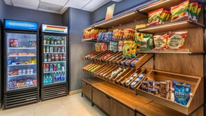 Un présentoir proposant des collations et des boissons, avec des options réfrigérées et non réfrigérées, notamment des chips, des en-cas et des boissons en bouteille.