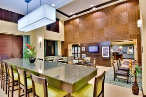 A spacious lobby with a central island, seating area, and a television screen. - Hampton Inn & Suites Moreno Valley (Moreno Valley)