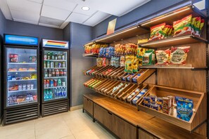 Un présentoir proposant des collations et des boissons, avec des options réfrigérées et non réfrigérées, notamment des chips, des en-cas et des boissons en bouteille.