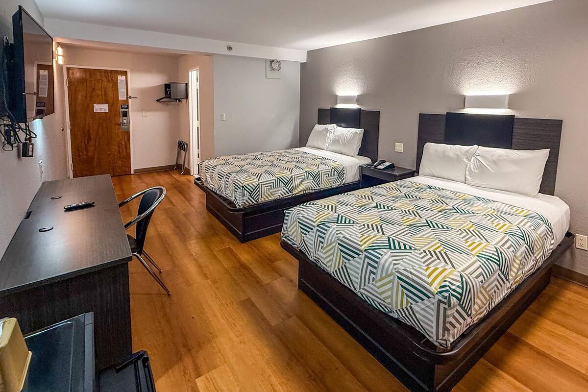 Ein Hotelzimmer mit zwei Betten, einem Schreibtisch und einem Stuhl.