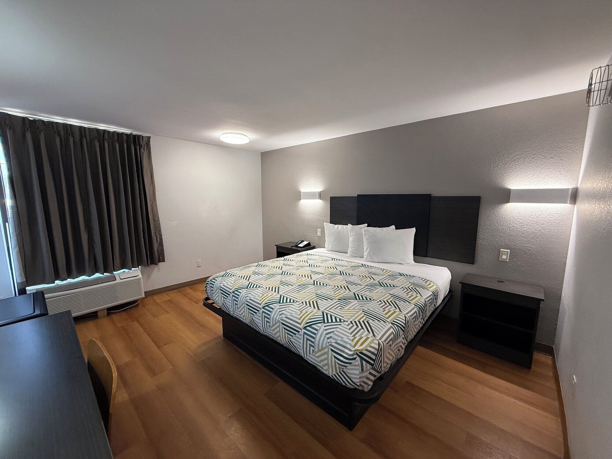 Une chambre d’hôtel moderne, dotée d’un grand lit, d’un bureau et d’un radiateur encastré.