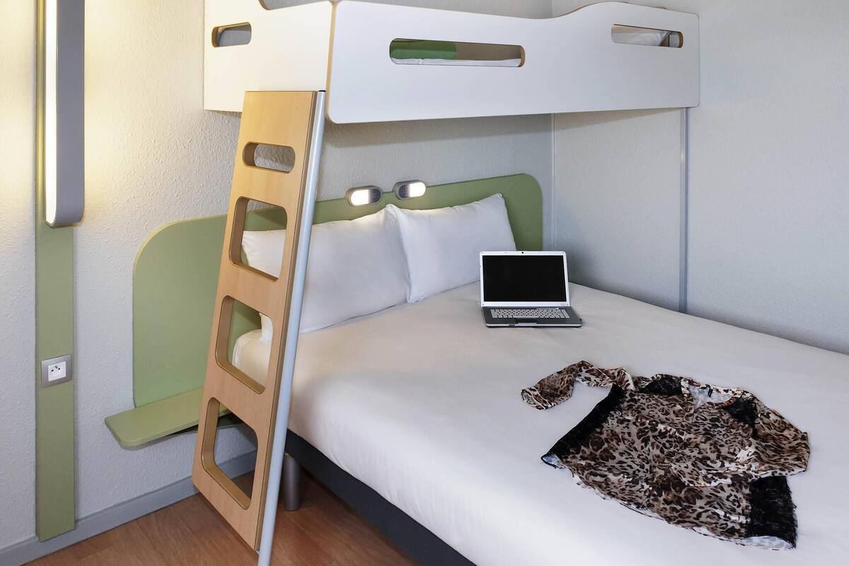 Un lit superposé avec un ordinateur portable et une couverture à motifs léopard sur le lit du bas.