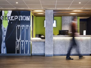 A reception area with a large wall graphic, a reception desk, and a person walking by.