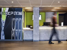 A reception area with a large wall graphic, a reception desk, and a person walking by.