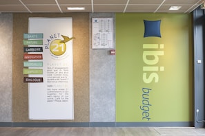 Un mur orné d’une grande affiche intitulée « PLANET 21 » et d’une enseigne indiquant « ibis budget ».