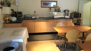 Una cocina compacta con comedor, equipada con tostadora, hervidor, microondas y pileta.