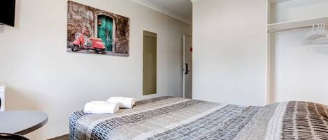 A hotel room with a bed, a chair, a painting, and a wardrobe.