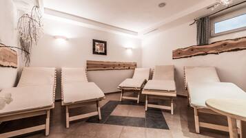 Relax in a serene spa room with four lounge beds and a large window offering a view of the sky.