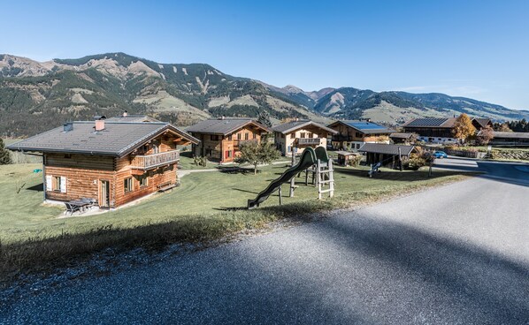 A mountain village with wooden houses, a playground, and a clear road. - Ferienhof Oberreit (Bruck an der Grossglocknerstrasse)