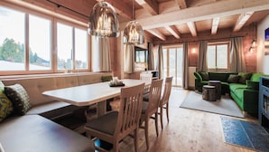 A wooden interior with a dining area, seating, and a green sofa. - Ferienhof Oberreit (Bruck an der Grossglocknerstrasse)
