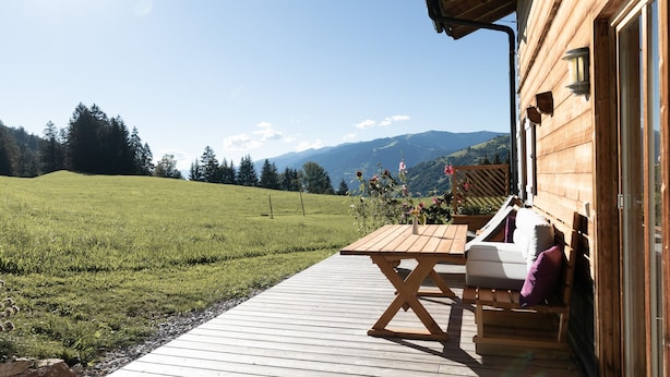 A wooden deck with a table and benches, overlooking a grassy field and mountains. - Ferienhof Oberreit (Bruck an der Grossglocknerstrasse)
