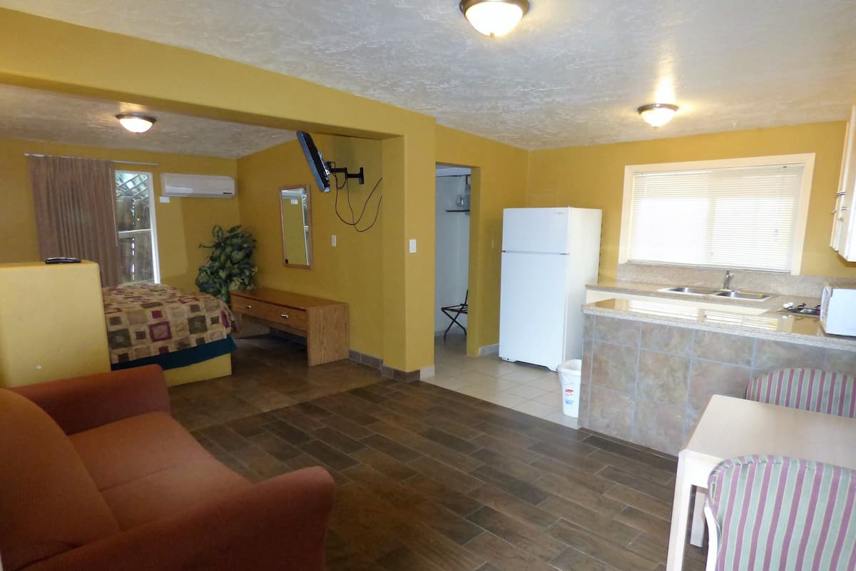Um espaço compacto com cozinha compacta, área de refeições e quarto com cama e um banco.