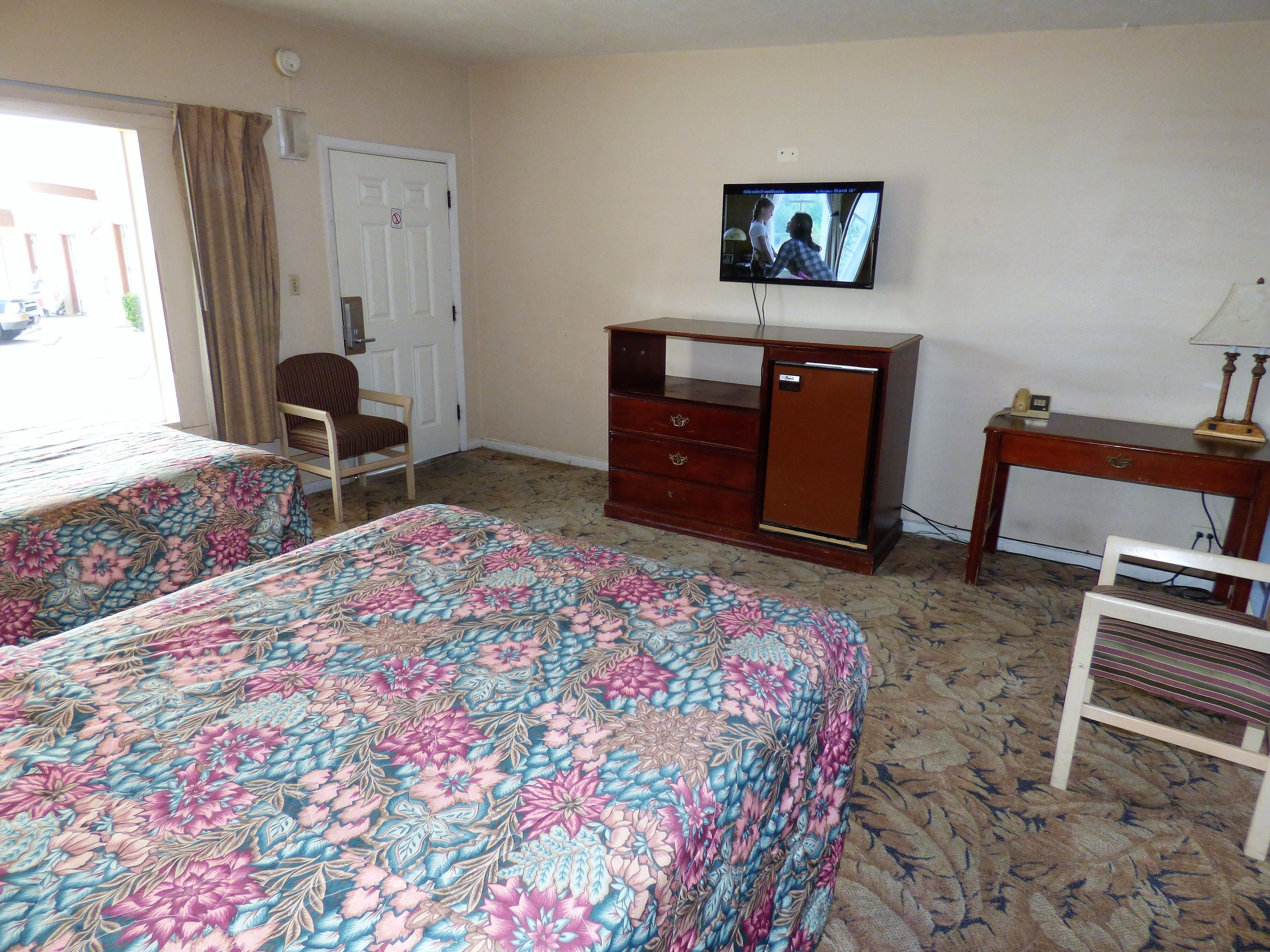 Une chambre d’hôtel avec deux lits, une télévision, un bureau et une chaise.
