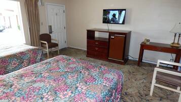 Une chambre d’hôtel avec deux lits, une télévision, un bureau et une chaise.