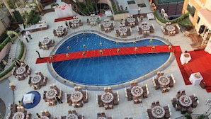 An outdoor pool area with multiple round tables and chairs, surrounded by a red carpet path. - Palace Hotel Vung Tau (Ho Chi Minh City)