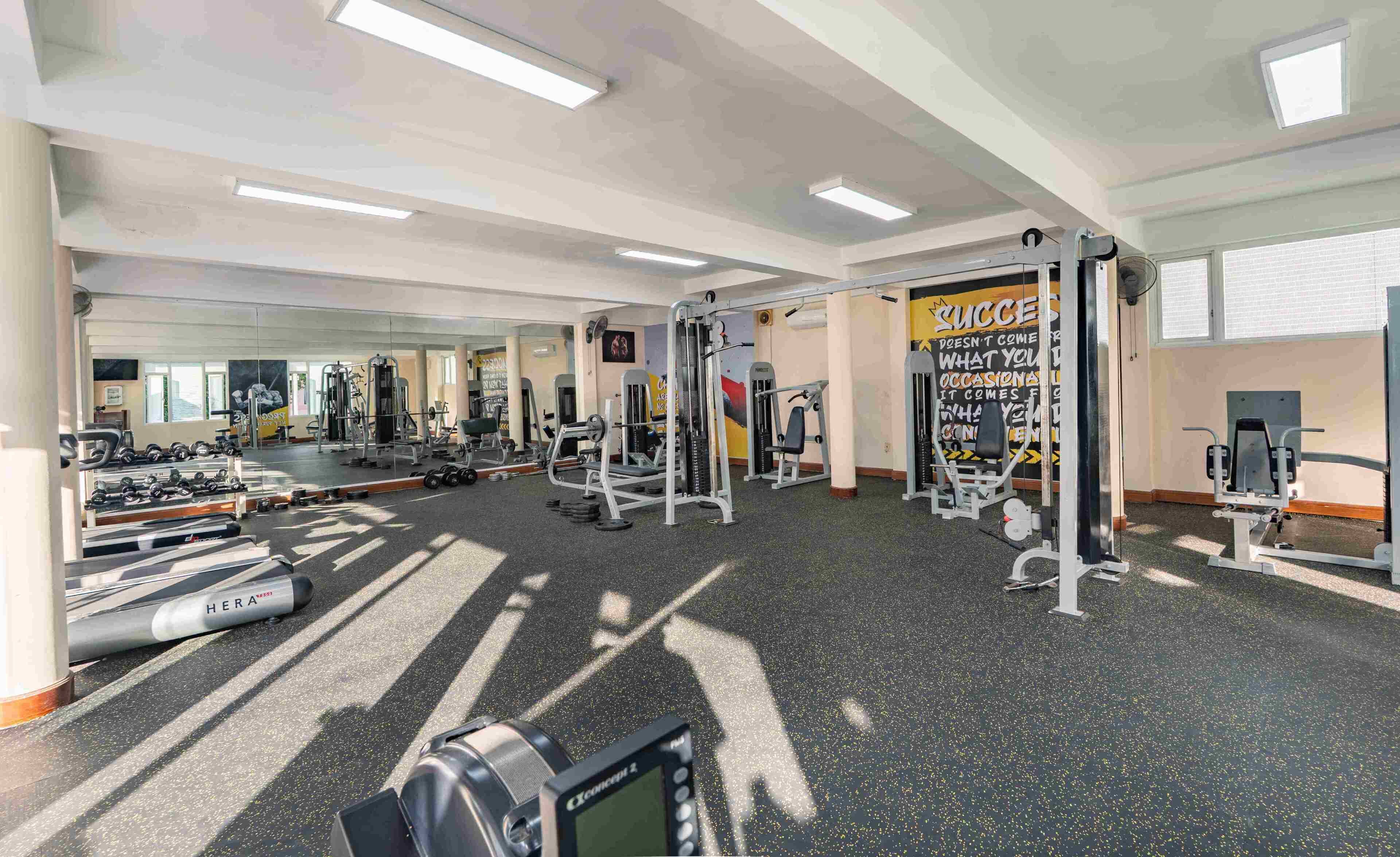 A gym with various exercise equipment, a mirror, and motivational posters.