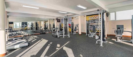 A gym with various exercise equipment, a mirror, and motivational posters.