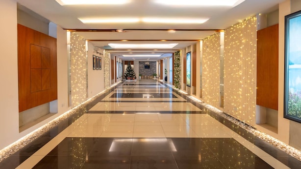 A hotel corridor with a checkered floor, wooden paneling, and a Christmas tree. - Palace Hotel Vung Tau (Ho Chi Minh City)
