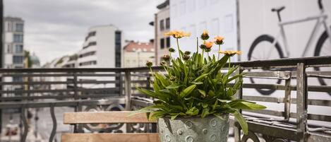 A wooden bench with a potted plant on a balcony.