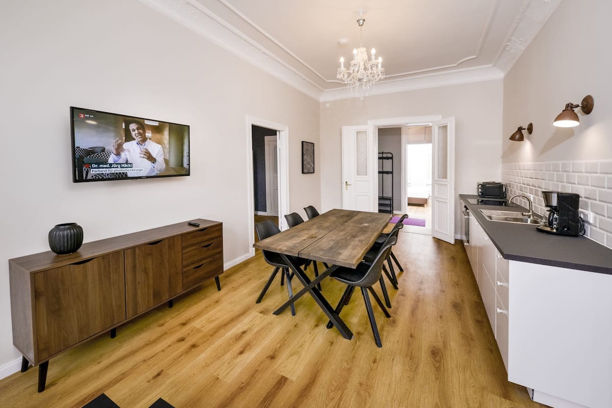 Een moderne keuken met een houten eettafel, zwarte stoelen en een ingebouwde oven.