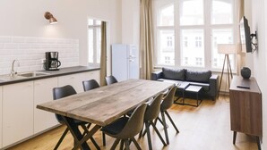 A modern kitchen with a wooden dining table, chairs, and a chandelier.