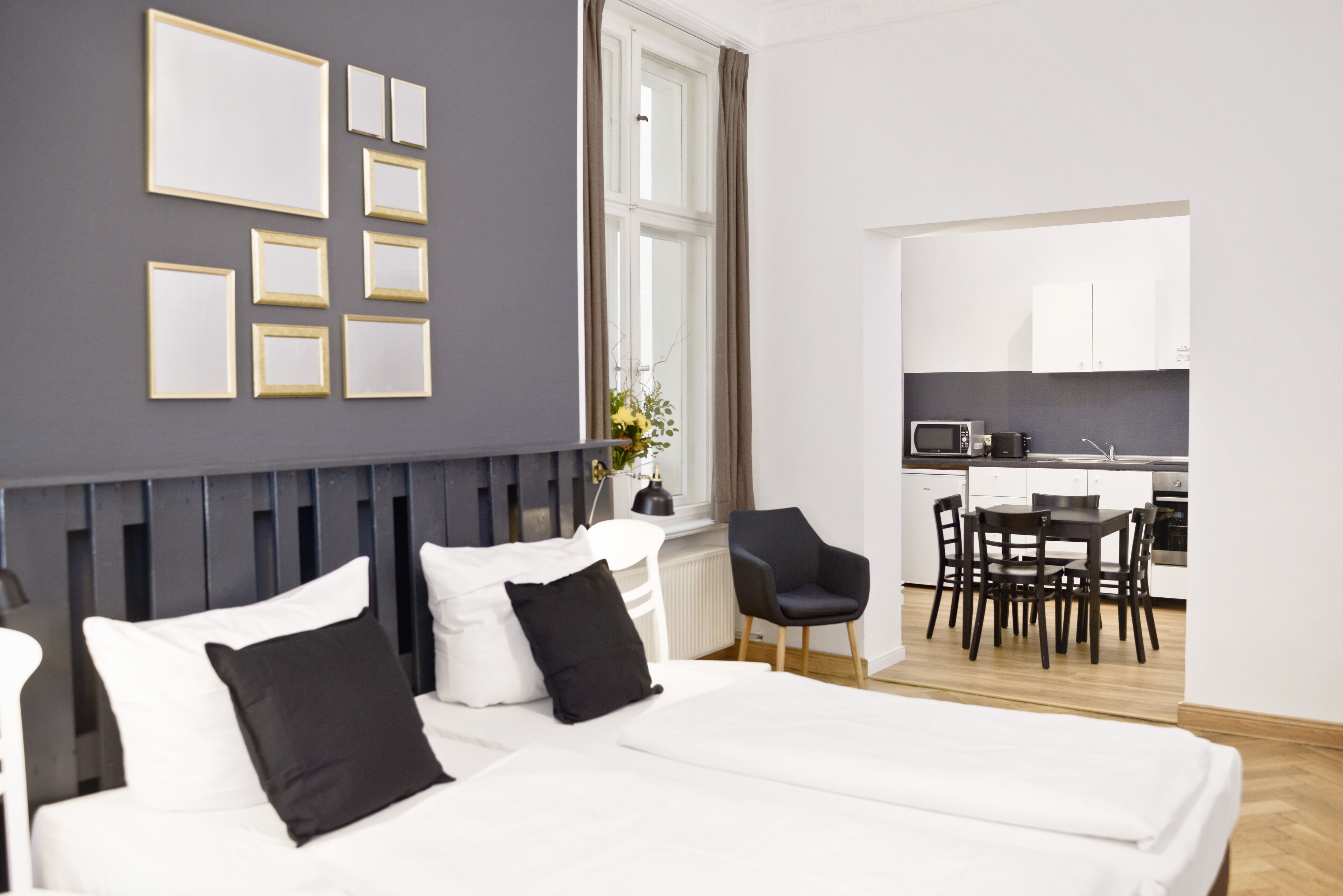 Ein modernes Hotelzimmer mit Bett, Schreibtisch und einer Küchenzeile.
