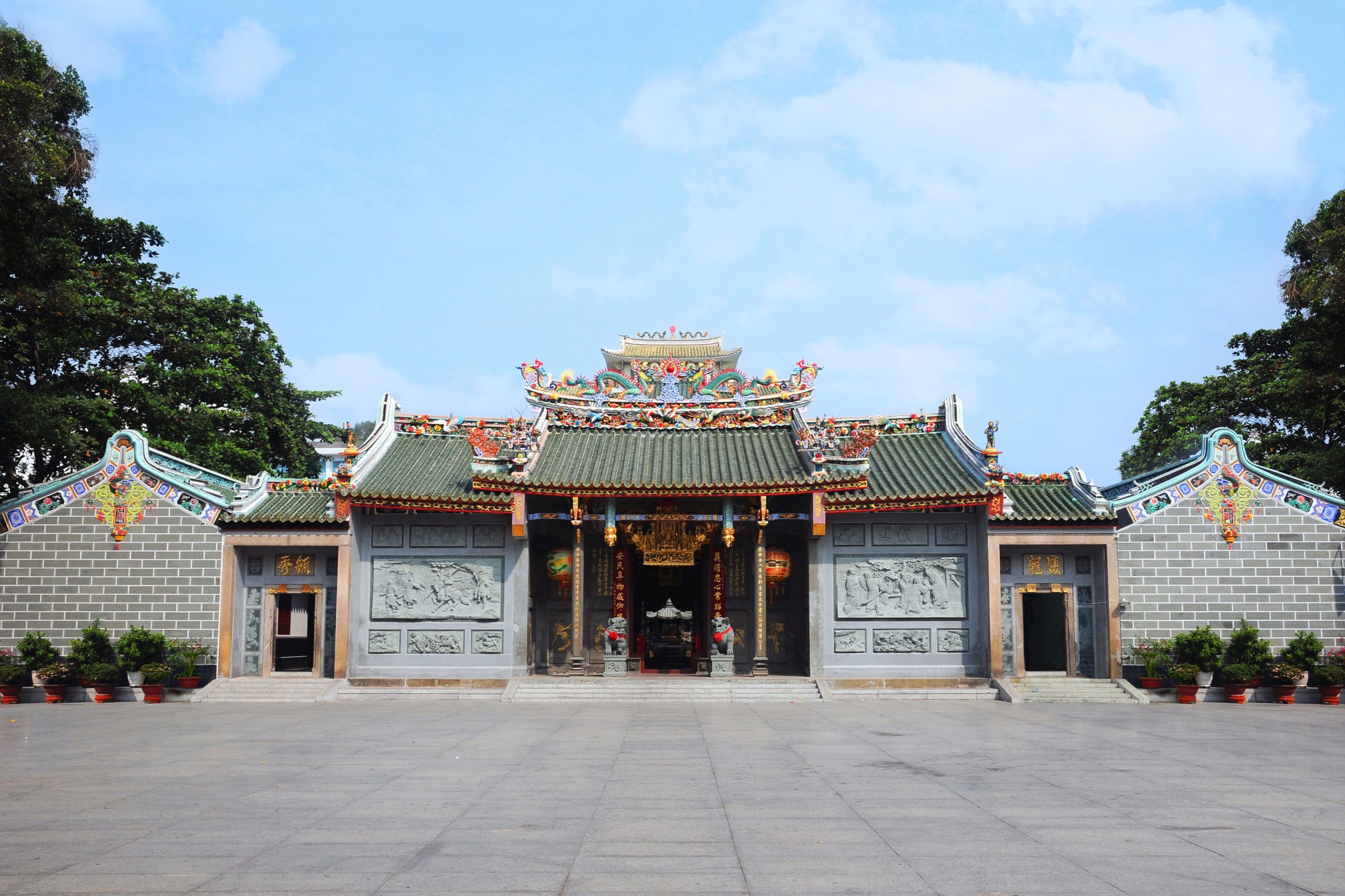 Um templo chinês tradicional com arquitetura elaborada, um amplo pátio aberto e estátuas.