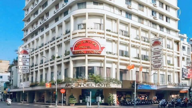 Un hôtel à plusieurs étages, doté de balcons, d’une enseigne bien visible et surplombant un ciel dégagé.