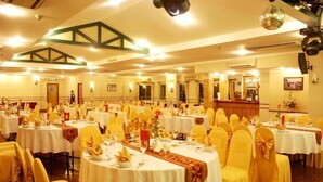 Une salle de banquet avec des tables rondes, des chaises jaunes et des nappes blanches.