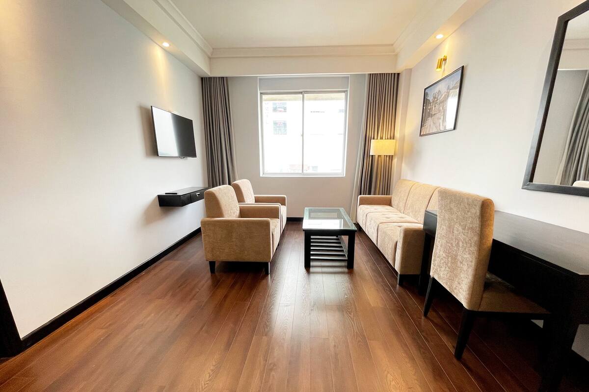A modern living room with a sofa set, a coffee table, and a TV mounted on the wall.
