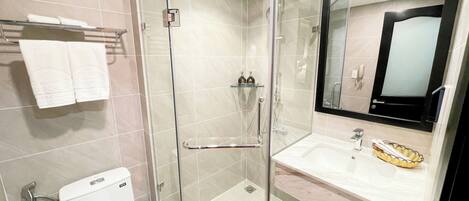 A modern bathroom with a glass-enclosed shower, a white toilet, a sink with a mirror, and a towel rack.