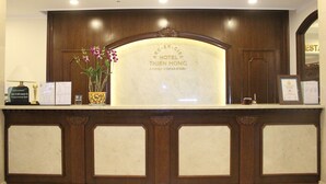 Un comptoir d’accueil d’hôtel avec un plateau en marbre et des panneaux en bois.