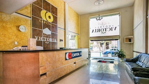 Ein Hotel-Empfangsbereich mit einer Rezeption, einer Uhr und einem Schild für das Victoria Hotel.