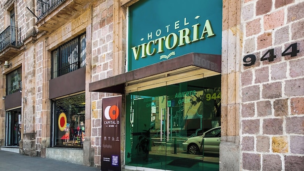 Ein Hotel namens 'Hotel Victoria' mit einer großen Glasfassade und einem parkenden Auto vor der Tür.