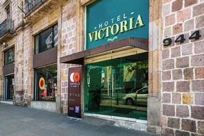 A hotel named 'Hotel Victoria' with a large glass facade and a visible car parked outside.