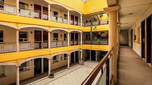 Ein mehrgeschossiges Atrium mit gelben Wänden, mehreren Balkonen und einer zentralen Treppe.