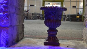 A large, ornate urn-like object in an indoor setting with a stone wall and a door marked "8000" in the background. - Knights Inn Greenville, TX (Greenville)