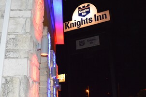 A Knights Inn sign with a stone wall backdrop and a neon sign.