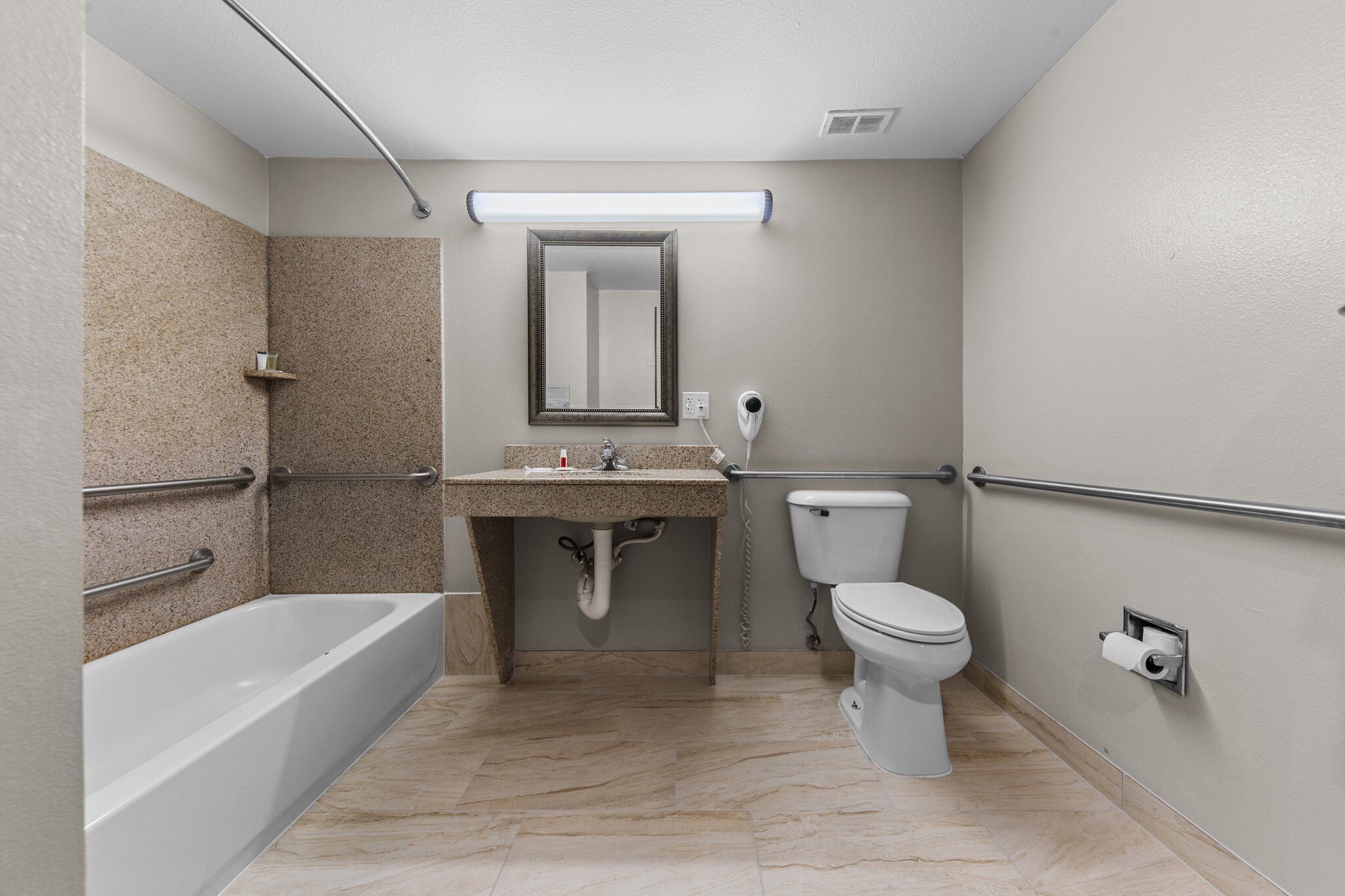 A bathroom with a bathtub, sink, toilet, and a mirror.