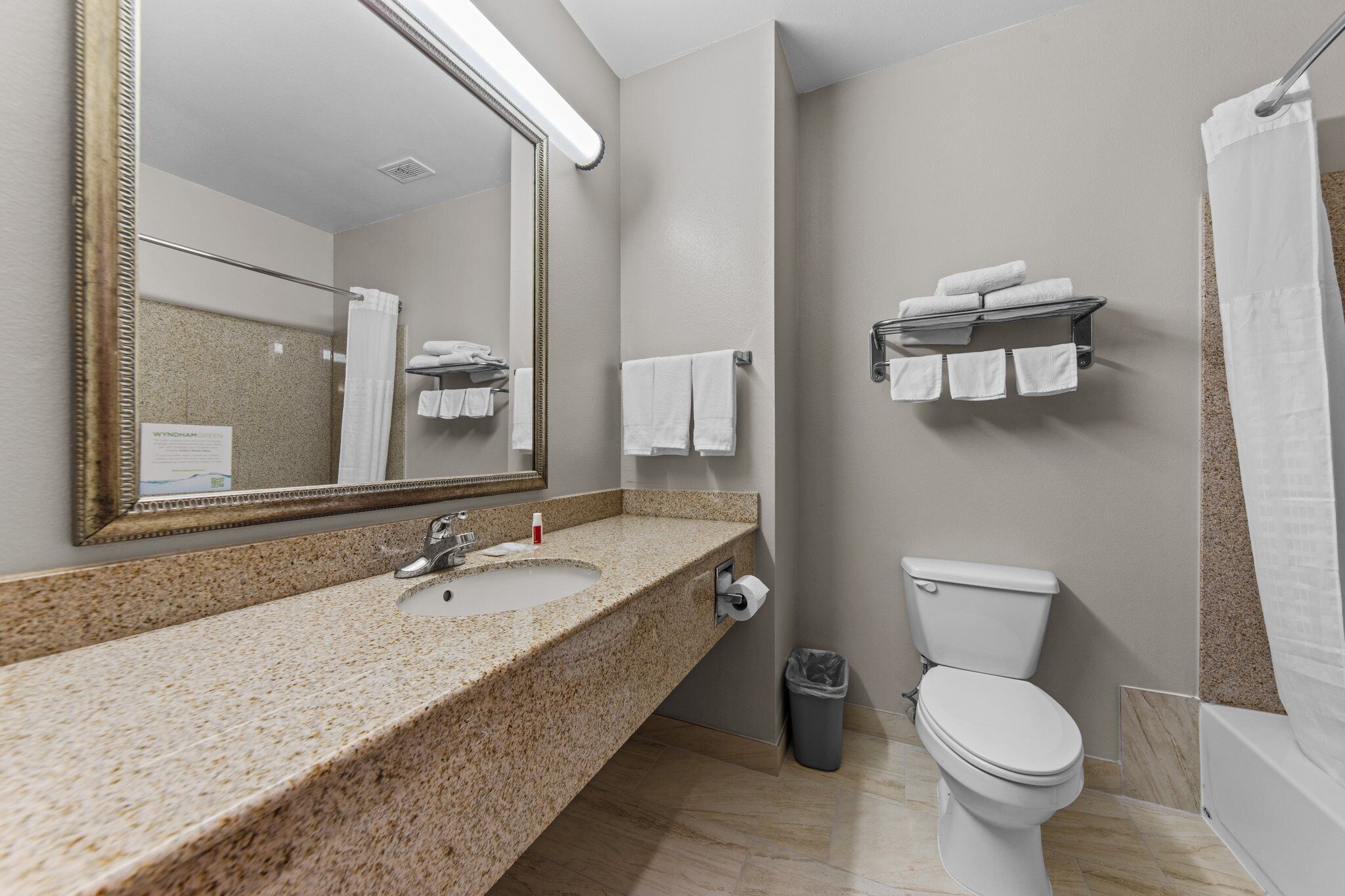 Une salle de bain avec un lavabo à dessus en granit, des toilettes, un miroir et un porte-serviettes.
